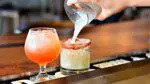 Close up of two drinks on bar with drink poured into one glass