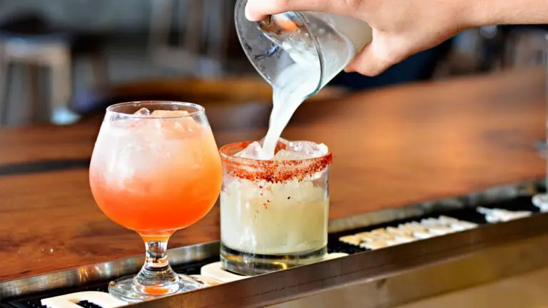 Close up of two drinks on bar with drink poured into one glass