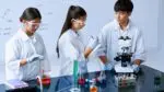 Three teens working in science classroom with science equipment in front of them