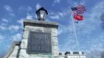 Close up of North Central College sign with flags waving in background