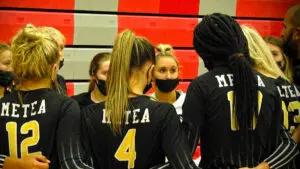 Metea Valley girls volleyball team huddles around each other.