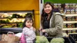 A mom and her daughter, who sits in the front of a shopping cart, at the West Suburban Community Pantry market.
