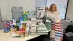A staff member with 360 Youth Services stands with donated home cleaning products for their housing clients.