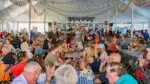 A crowd sits underneath a tent to eat and drink during Naper Settlement's Oktoberfest