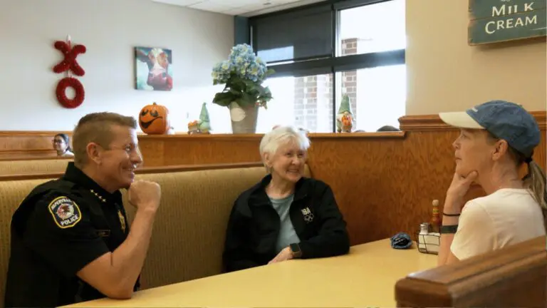 Police chief and two women sit at a table with one another