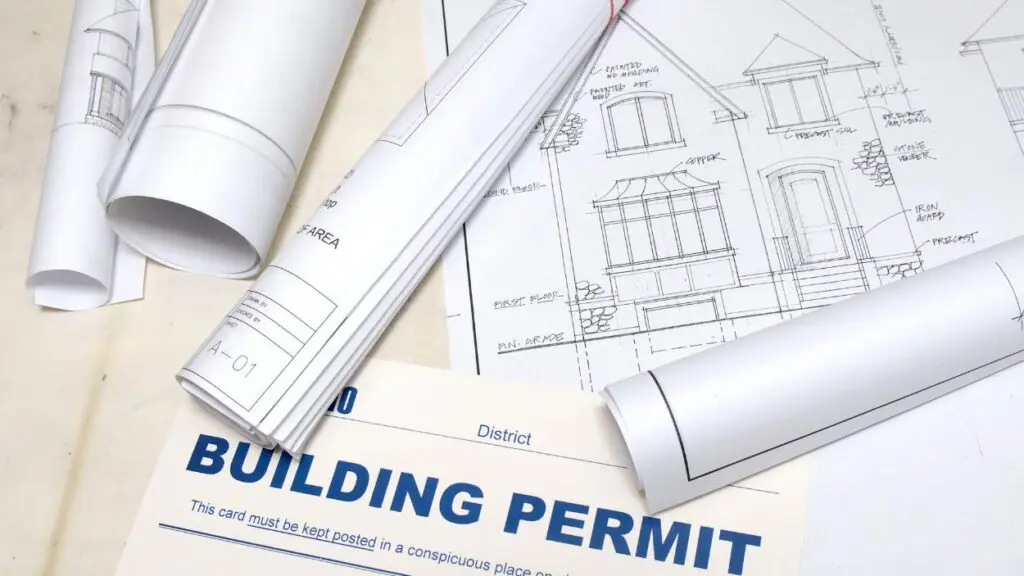building design plans rolled up with a building permit slip nearby