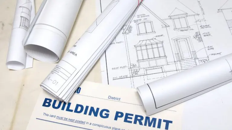building design plans rolled up with a building permit slip nearby