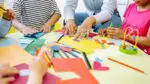Table with arts and crafts with kids hands visible working on projects