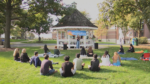 Students gather in Naperville's Central Park to listen to a person speak