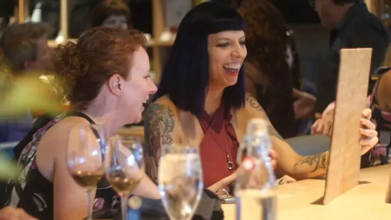 Two women view a restaurant menu and smile