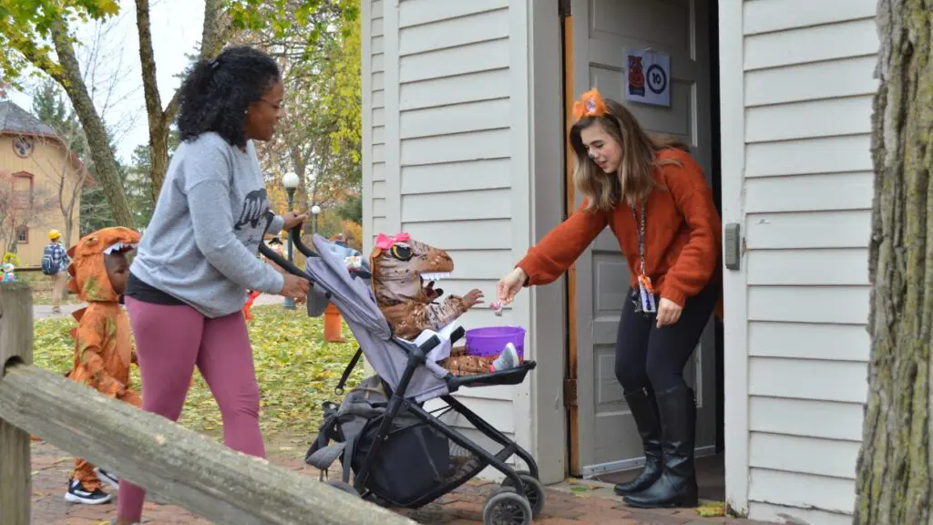 A woman in a costume hands candy to a trick-or-treater