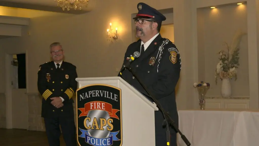 Close up of Andy Winckler at CAPS award podium with Fire Chief Mark Puknaitis watching him speak