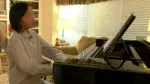 A girl sits at a piano and plays a song