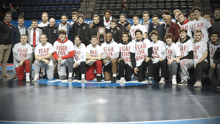 The North Central men's wrestling team takes a group photo with their national placement trophy