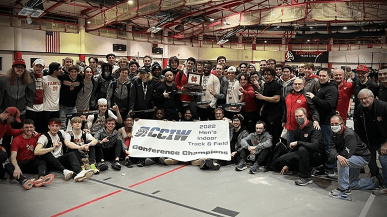 north central's men's indoor track and field team pose for a picture as a group with the CCIW championship banner