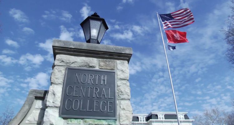 sign for North Central College in Naperville, flags blowing overhead