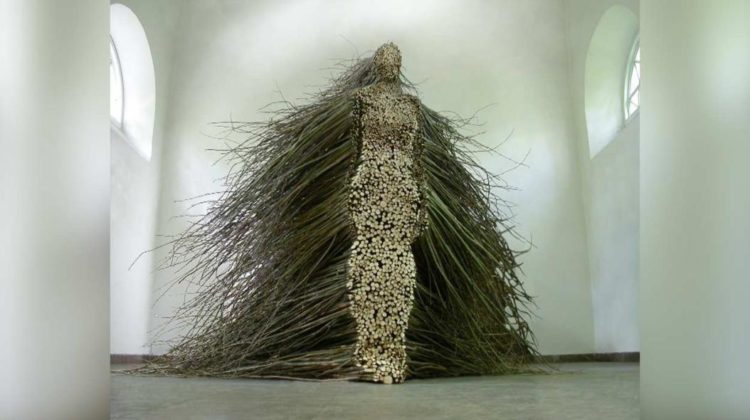 An exhibit made out of a person made out of tree branches.
