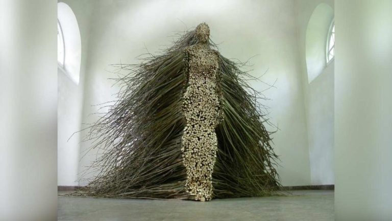 An exhibit made out of a person made out of tree branches.
