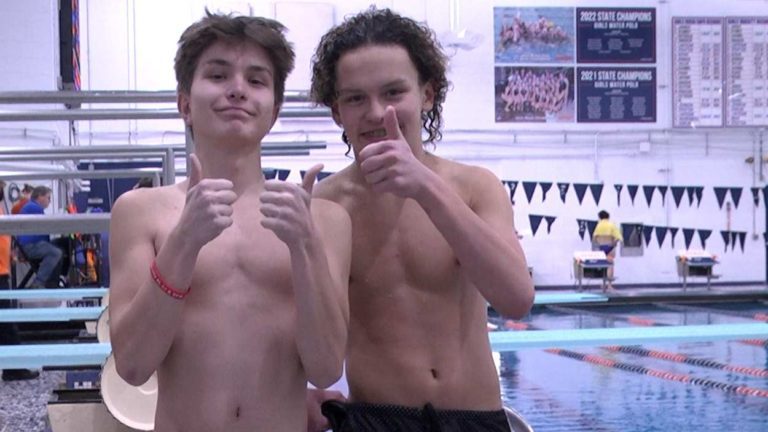 Two swimmers smile and hold thumbs up