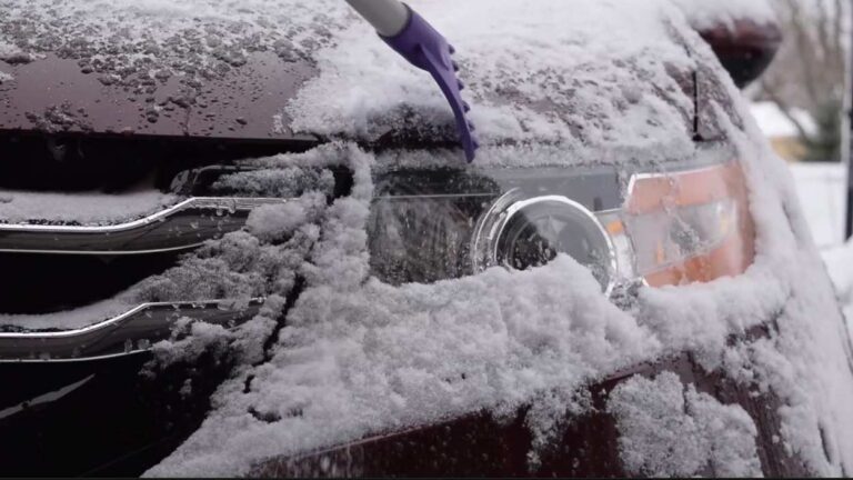 snow and ice on front of a car by headlight after wintry weather