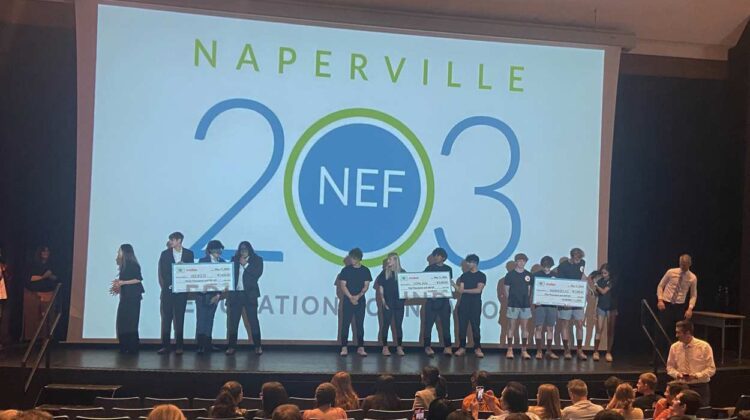 District 203 students on stage with large checks at INCubatoredu Pitch Night