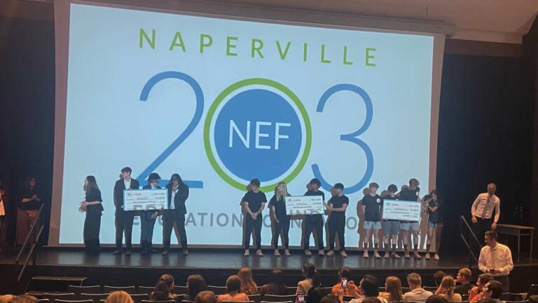 District 203 students on stage with large checks at INCubatoredu Pitch Night