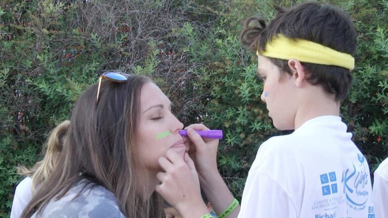 Kid paints glow stick on mom for last G.L.O.W. 5K run