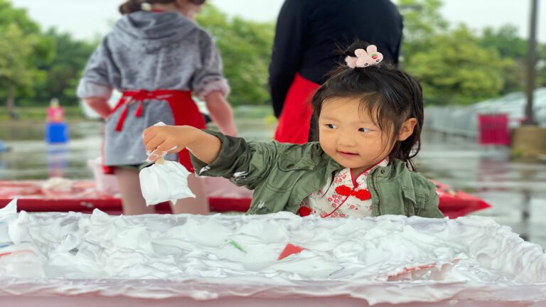 Little girl playing with shaving cream during Mess Fest at the DuPage Children's Museum in Naperville