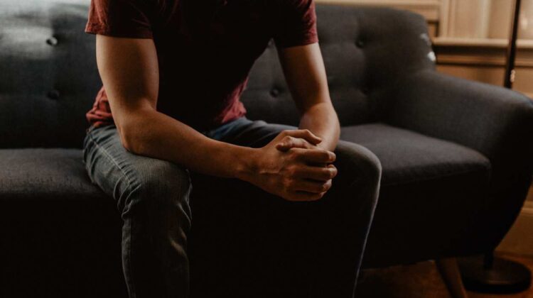 person sitting on couch with hands clasped