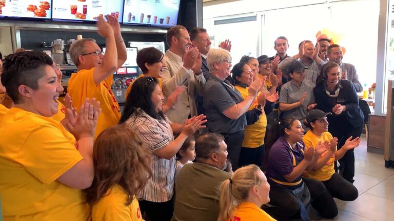 Happy people clapping inside McDonalds at reaching $1M fundraising goal