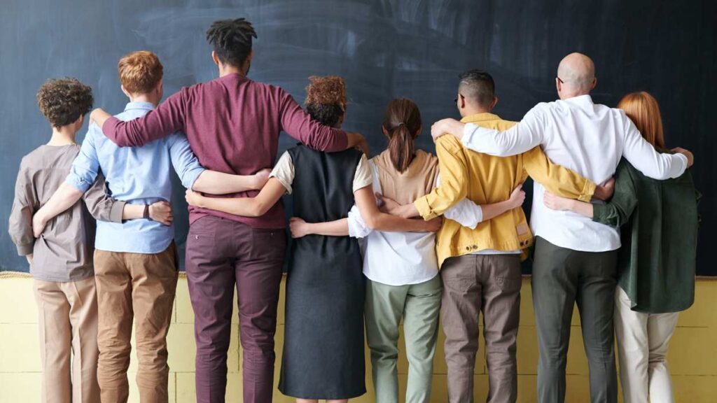 file image of group of people with arms around each other in front of blackboard