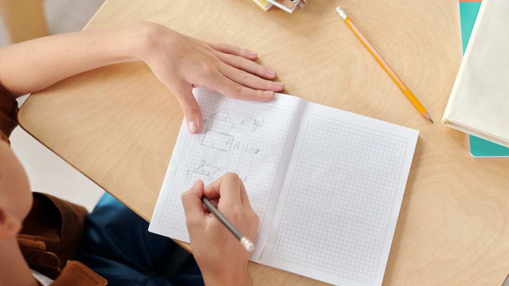 Overhead shot of student at desk with notebook open ready to write