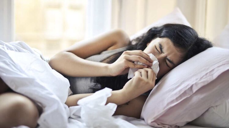File image of woman laying in bed blowing nose with kleenex