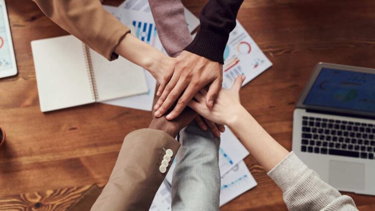 Various hands joined over table