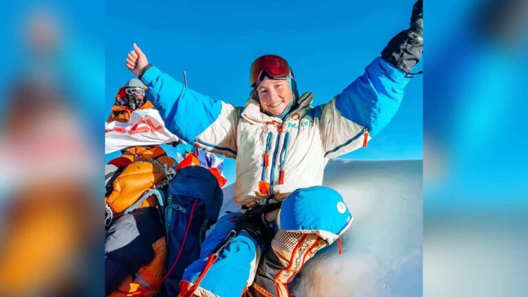 Naperville native Lucy Westlake in cold weather gear sitting atop a mountain