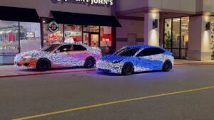 Two lit-up cars in front of building