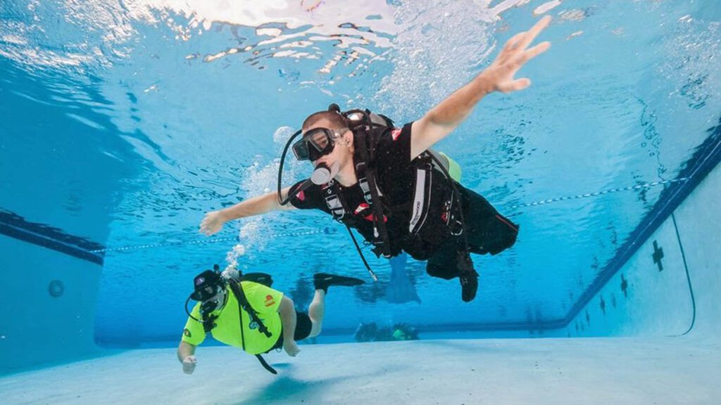 Diveheart participant scuba dives with instructor in a pool