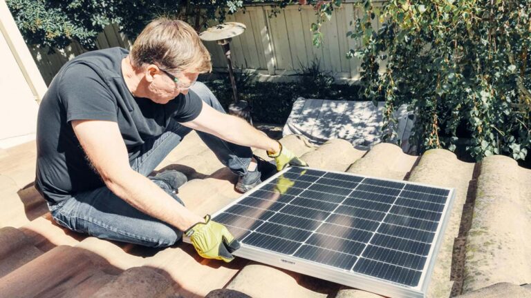 Man installs solar panel on roof of home