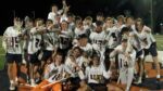 Huskies lacrosse players celebrate with the Naperville Cup trophy.