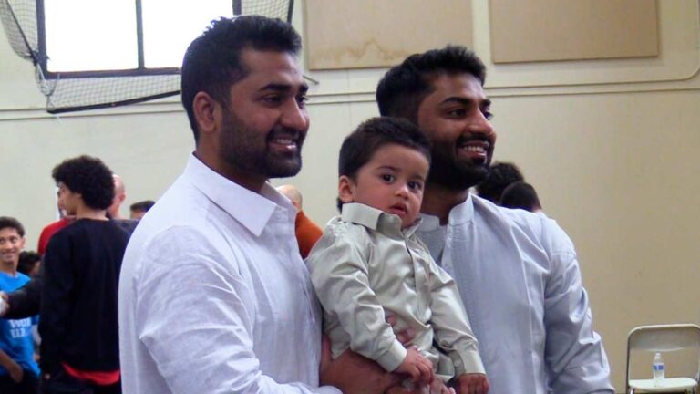 Two men holding a child at the ICN Eid celebration