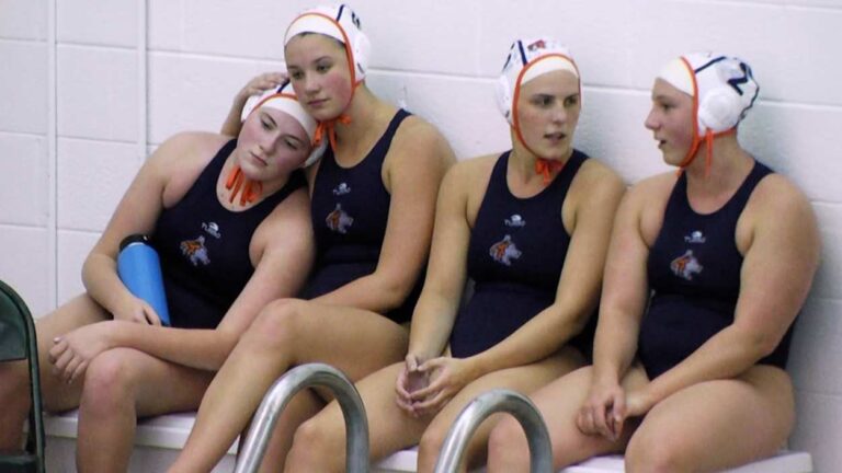 Naperville North girls water polo players hug and talk before winning DVC title.