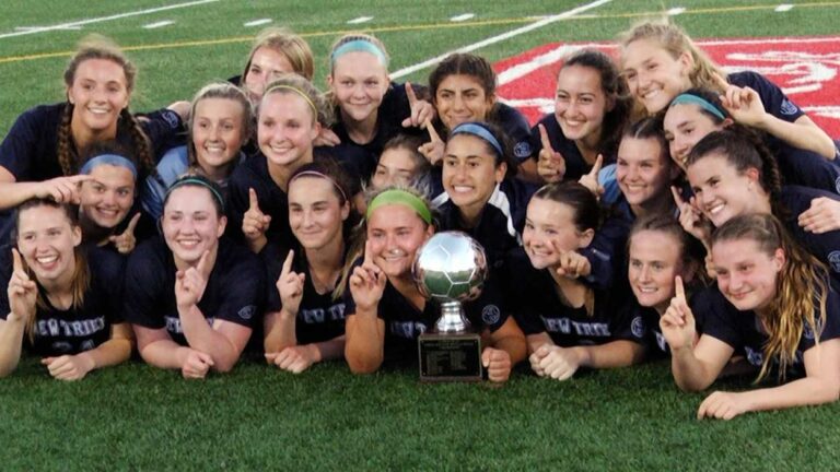 New Trier girls soccer players smile and pose with the Ed Watson Naperville Invite Championship trophy.