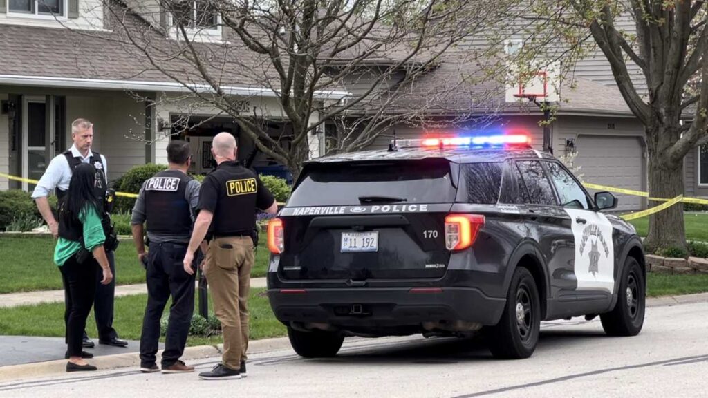 Naperville police officers standing next to squad car at site of shooting investigation