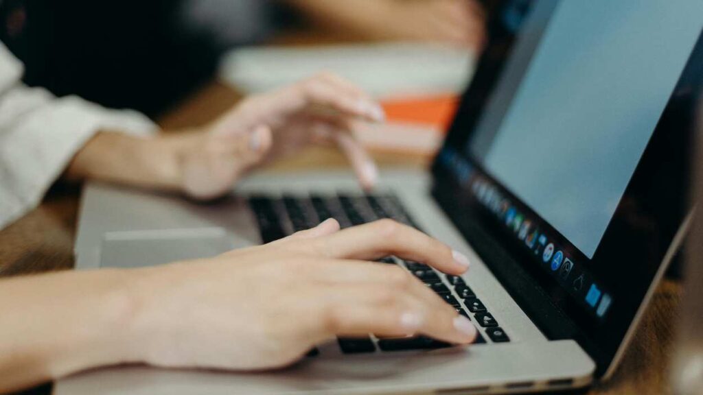 close up of hands typing on computer keyboard