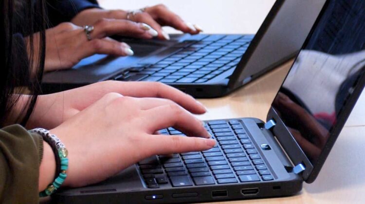 Students typing on a laptop.