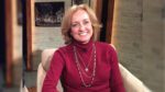 Janet Derrick sits in an armchair, smiling at the camera.