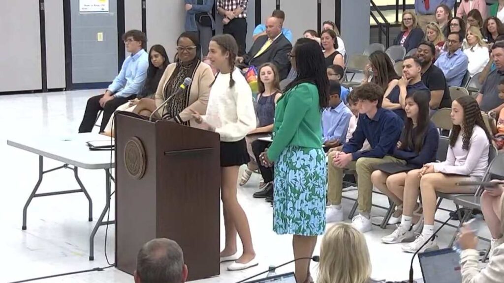 student from District 203’s Superintendent’s Student Advisory Council stands in front of podium at board of education meeting