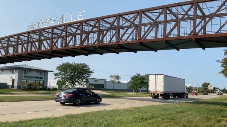 Traffic going under Naperville sign and bridge on Route 59