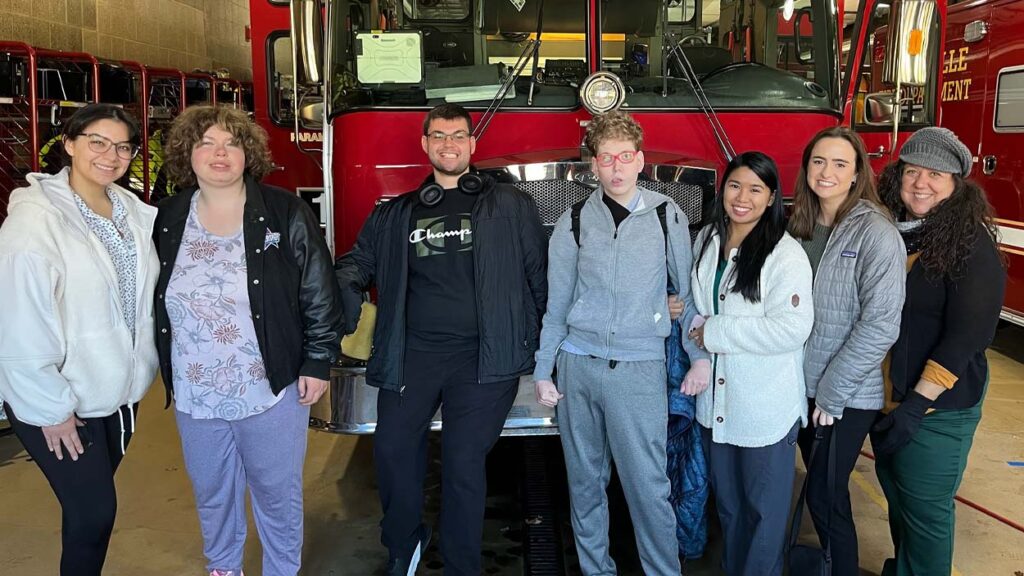A group of people poses in front of a fire truck