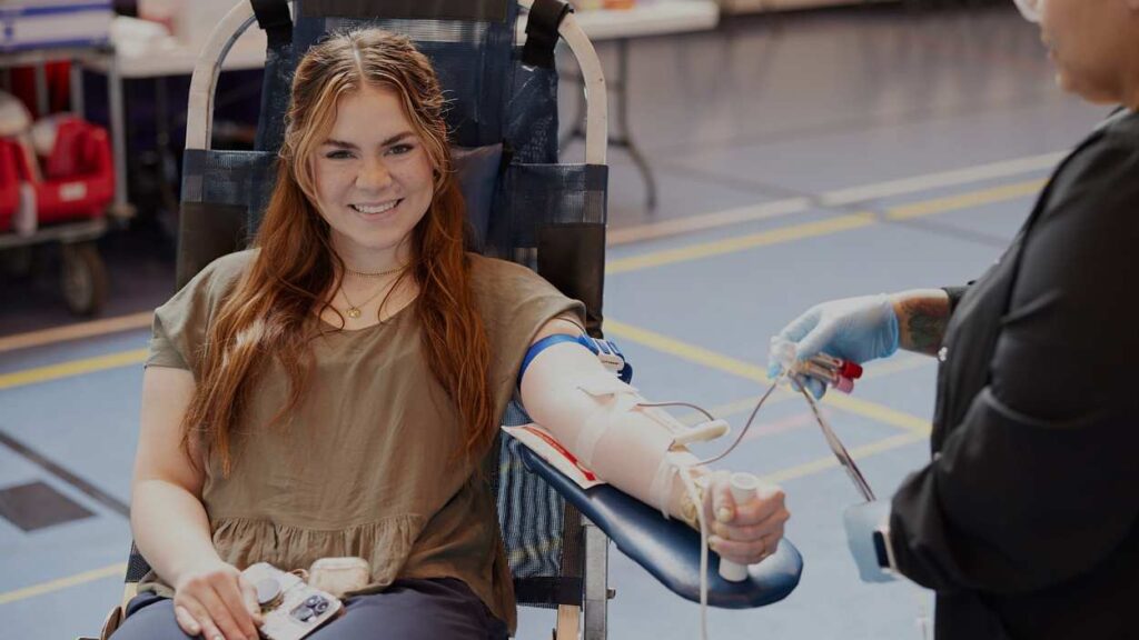 Blood donor seated in chair, giving blood
